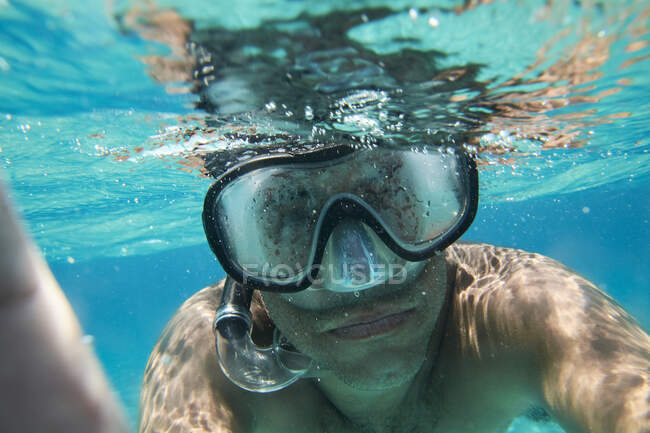 Ritratto di uomo con occhiali subacquei e boccaglio che prende selfie sott'acqua — Foto stock