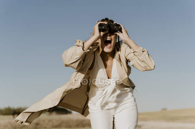 Female traveller looking through binoculars — Stock Photo
