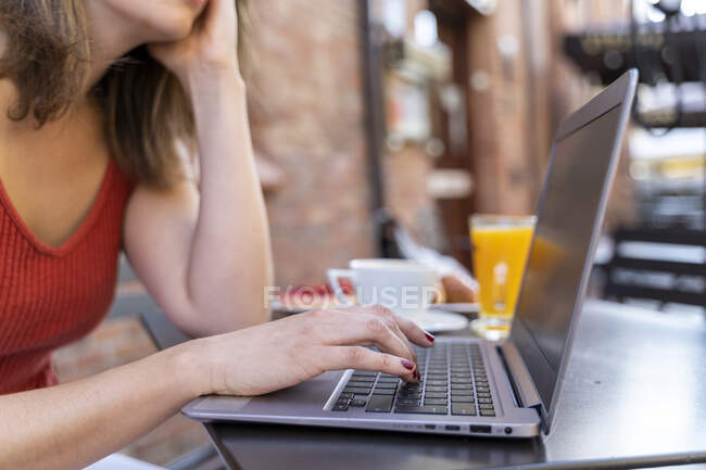 Young blogger sitting at street cafe working on laptop, close-up — Stock Photo