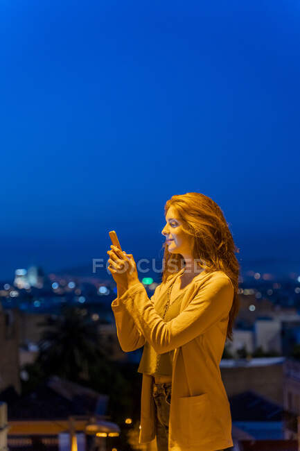 Giovane donna che utilizza lo smartphone su un punto di vista all'ora blu, Barcellona, Spagna — Foto stock