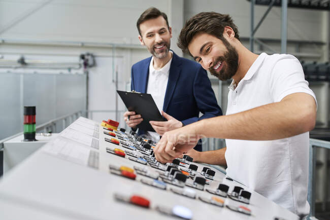 Businessman and employee talking at control panel in a factory — Stock Photo