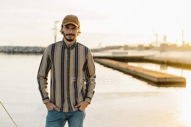 Портрет мужчины в бейсболке и полосатой рубашке на закате — стоковое фото
