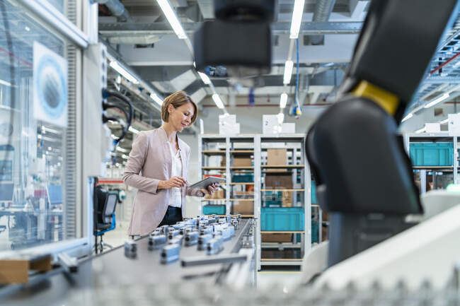 Donna d'affari con tablet in una moderna sala di fabbrica — Foto stock