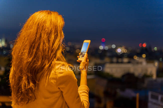 Jeune femme utilisant un smartphone sur un point de vue à l'heure bleue, Barcelone, Espagne — Photo de stock