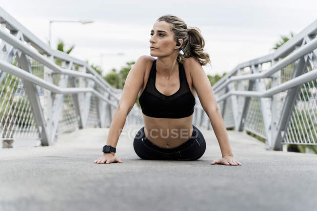 Donna sportiva con le cuffie, in allenamento su un ponte — Foto stock