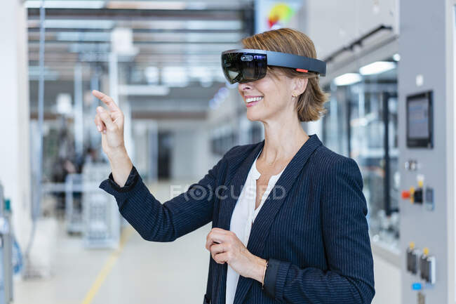 Улыбающаяся деловая женщина в очках AR на современной фабрике — стоковое фото