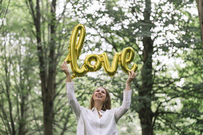 Young woman holding the word love in a forest — Stock Photo
