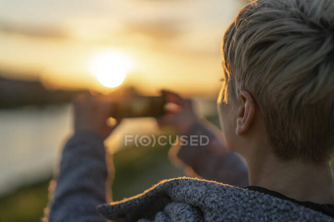 Vista posteriore della donna che scatta foto al tramonto, primo piano — Foto stock