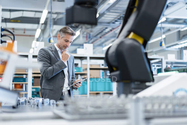 Homme d'affaires avec tablette dans un hall d'usine moderne — Photo de stock