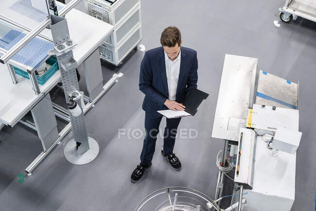 Empresário com prancheta em uma fábrica — Fotografia de Stock