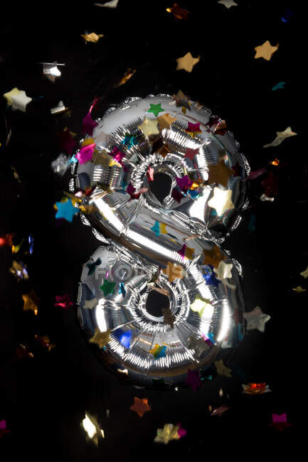 Palloncino d'argento e coriandoli per l'ottavo compleanno davanti allo sfondo nero — Foto stock