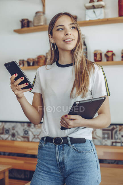 Retrato de una mujer joven sosteniendo una tableta en un café - foto de stock
