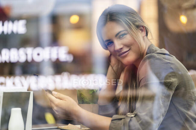 Young businesswoman in a cafe, seen through window — Stock Photo