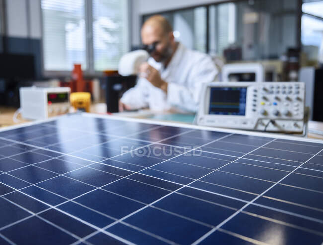 Солнечная панель и техник с микроскопом в фоновом режиме — стоковое фото
