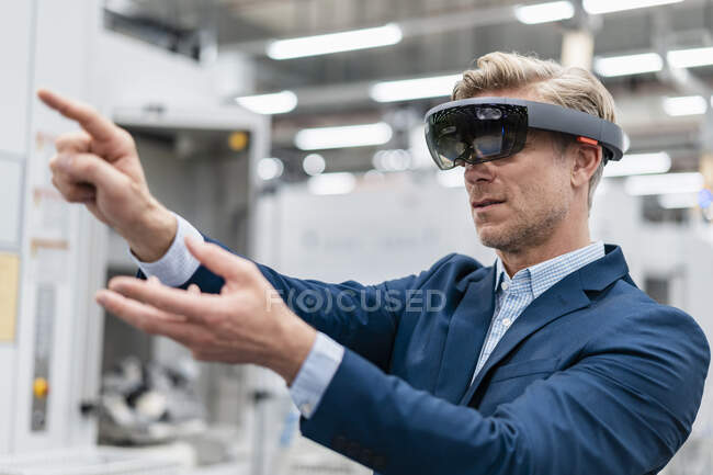Businessman wearing AR glasses in a modern factory — Stock Photo