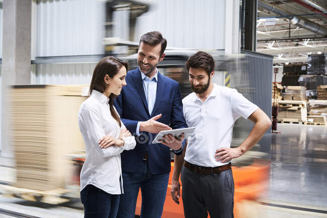 Lächelnder Geschäftsmann mit Tablet und Mitarbeiter im Gespräch in einer Fabrik — Stockfoto