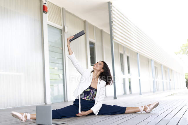 Dançarina de balett feminina sentada no chão, usando tablet e laptop — Fotografia de Stock