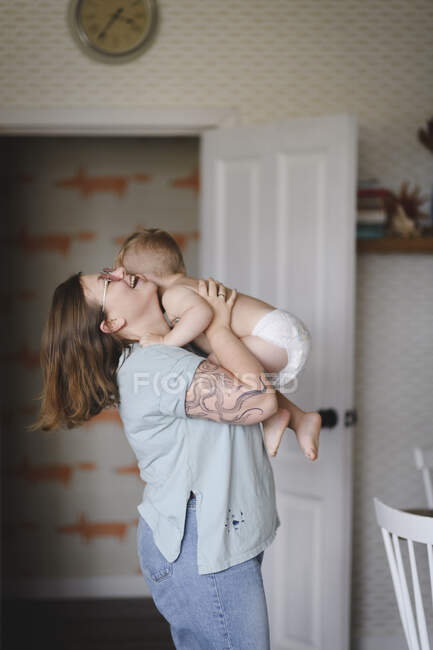 Сміється мати грає зі своїм маленьким сином на кухні — стокове фото