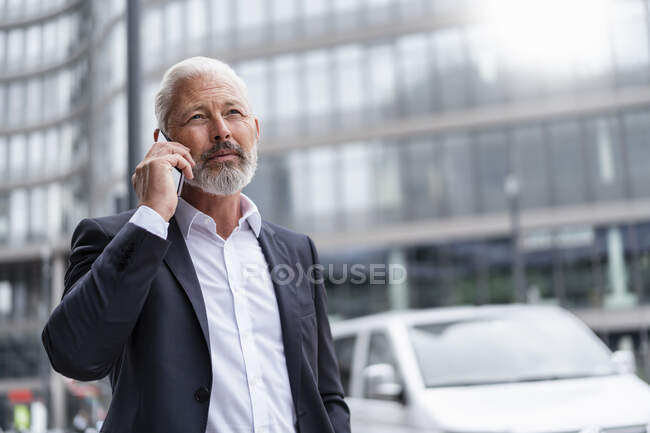 Mature businessman on cell phone in the city — Stock Photo