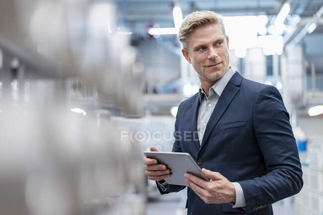 Empresario con tablet en una fábrica moderna - foto de stock