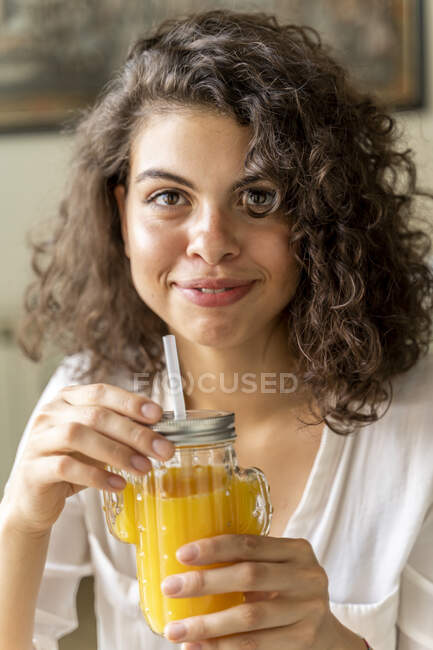Портрет усмішки молодої жінки зі склом апельсинового соку. — стокове фото
