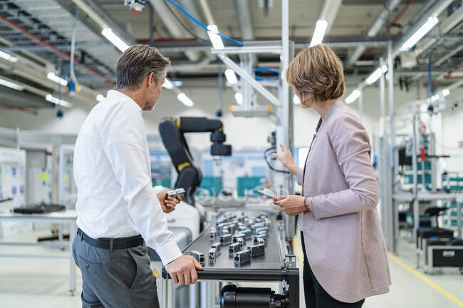 Businessman and businesswoman talking in a modern factory hall — Stock Photo