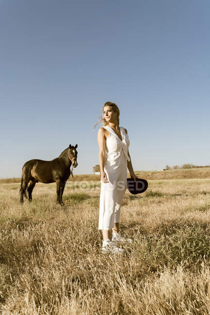 Mujer viajera con sombrero de paja, caballo en el fondo - foto de stock