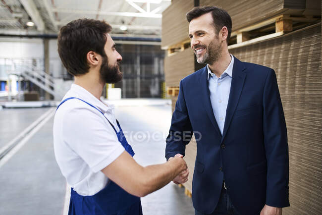 Homme d'affaires et travailleur serrant la main dans une usine — Photo de stock