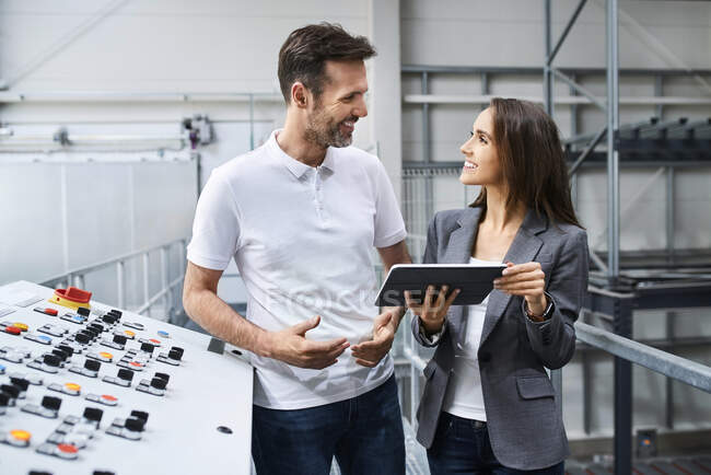 Businesswoman and employee talking at control panel in a factory — Stock Photo