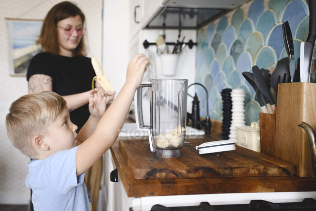 Mutter und Sohn beim Kochen von Bananenpfannkuchen in der heimischen Küche — Stockfoto