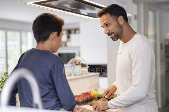 Отец и сын готовят дома на кухне вместе — стоковое фото