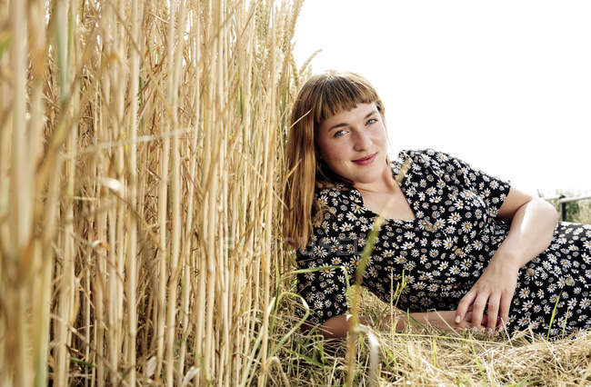 Porträt einer lächelnden jungen Frau in einem Kleid mit floralem Muster in der Natur — Stockfoto