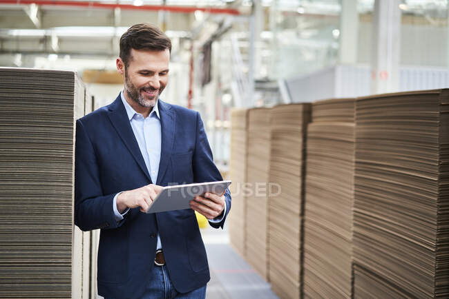 Smiling businessman using tablet in factory warehouse — Stock Photo