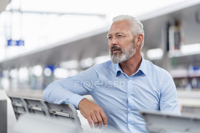 Homme d'affaires mature assis au quai de la gare regardant autour — Photo de stock