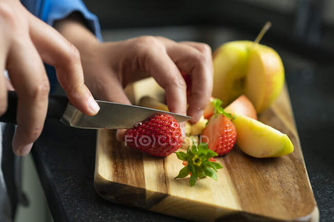 Femme coupant des fruits dans sa cuisine, gros plan — Photo de stock