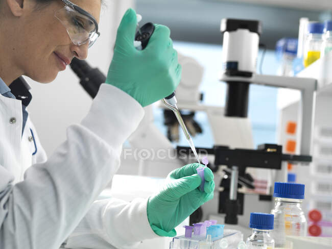 Biotech Research, Muestra de pipeteo científico en un vial listo para su análisis durante un experimento en el laboratorio - foto de stock