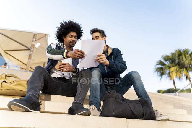 Two casual businessmen sitting on stairs working on paper — Stock Photo