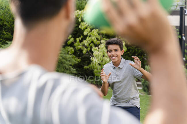 Padre e hijo jugando con fútbol americano en el jardín - foto de stock