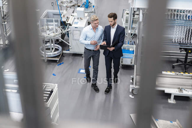 Dois empresários com prancheta conversando em uma fábrica — Fotografia de Stock