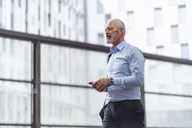 Uomo d'affari maturo con cellulare in movimento — Foto stock