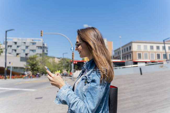 Mujer joven usando smartphone en puente peatonal en Barcelona - foto de stock