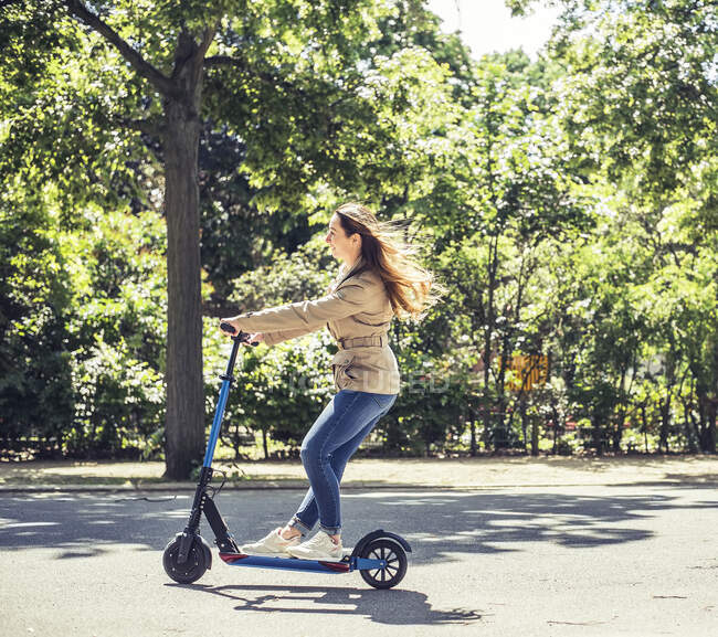 Sorridente donna cavalcando E-Scooter — Foto stock