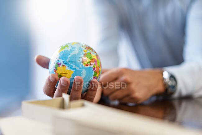 Close-up of businessman holding miniature globe in office — Stock Photo