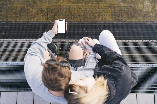 Молода пара сидить сходами, дивлячись на смартфон — стокове фото