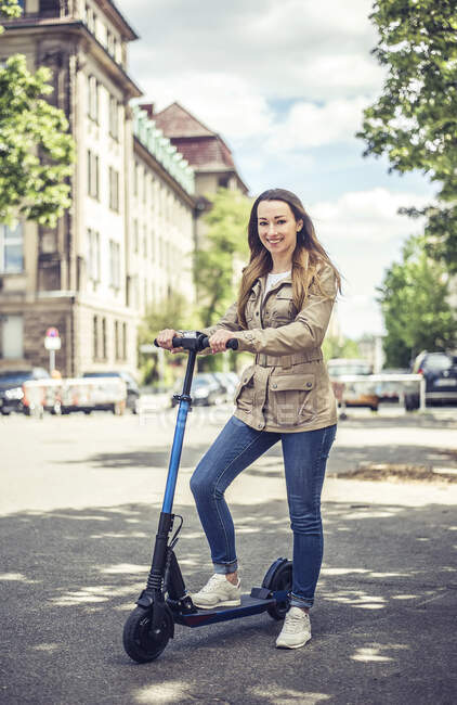 Portrait of smiling woman with E-Scooter — Stock Photo