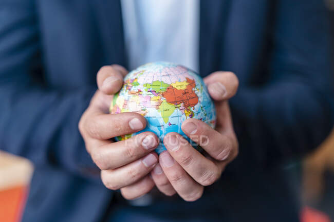 Close-up of businessman holding miniature globe in office — Foto stock