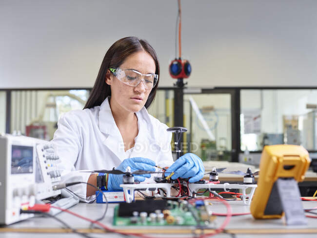 Técnico feminino trabalhando em laboratório de pesquisa, conectando plugue de drone — Fotografia de Stock