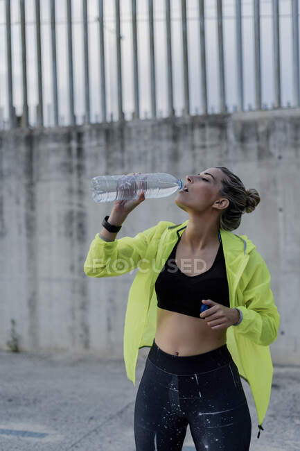 Donna sportiva che beve da una bottiglia d'acqua — Foto stock