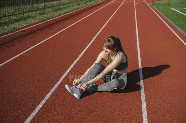 Sportlerin auf der Rennbahn bindet Schuhe — Stockfoto