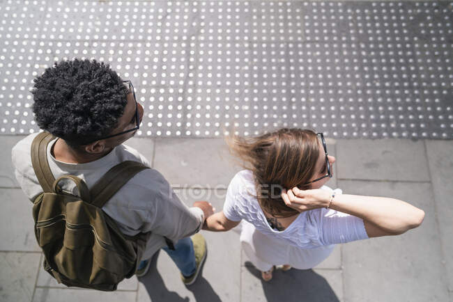 Young couple standing hand in hand at roadside looking right — Stock Photo